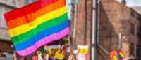 Pride parade flags with rainbow colors with city building background